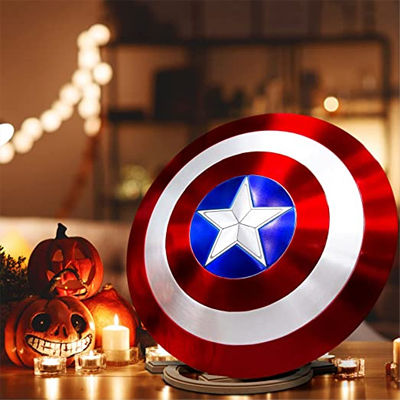 Real Captain America shield replica is presented on a stand and a couple of pumpkins are standing next to it lit by candlelight.
