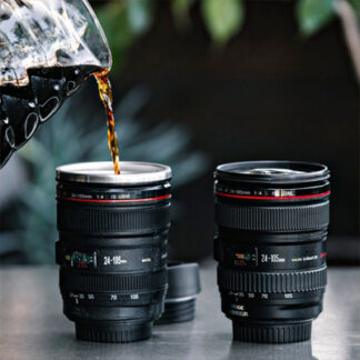 A coffee mug in a camera lense shaped is displayed pouring coffee in it.