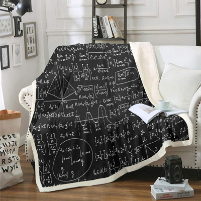 A black blanket is displayed laid on a sofa and on the blanket there are mathematical equations and drawings all over it. Looks like a blackboard from a calculus class in shape of a blanket.