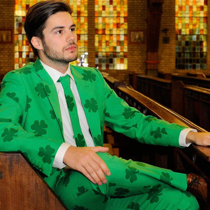 A man in a bar is sitting wearing a full set shamrock suit which has shamrock patterns and a monochrome tone.