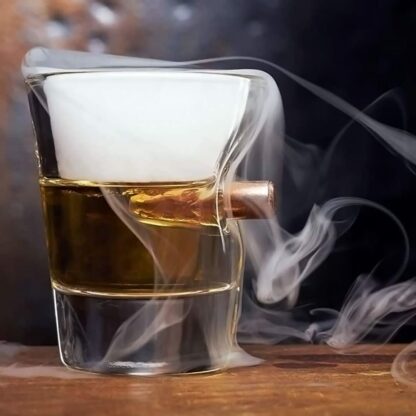 A shot glass with a 0.308 bullet embedded in it is filled with a beverage smoking from the top.