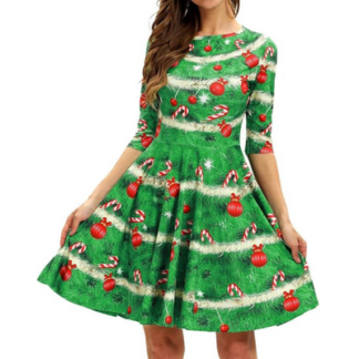 A woman is wearing an above knee skirted dress which is printed with a Christmas tree pattern with ornaments on it.
